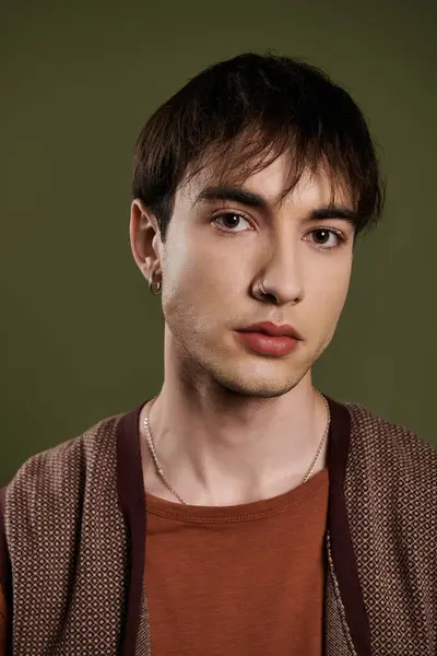 A young man in a brown sweater poses against a vibrant green background. — Stock Photo