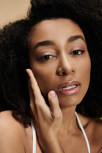 A close-up portrait of a beautiful African American woman with natural makeup, her hand gently caressing her cheek. — Stock Photo