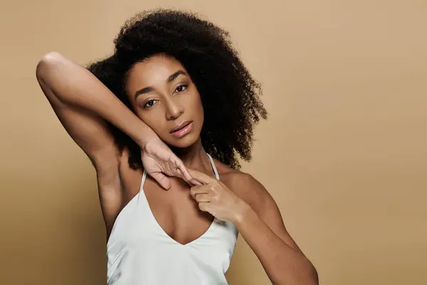 Una bella donna afroamericana posa con trucco naturale su uno sfondo beige. — Foto stock