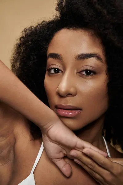 A close-up portrait of a beautiful African American woman with natural makeup on a beige background. — Stock Photo