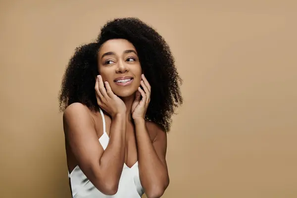 Um retrato de uma bela mulher afro-americana com maquiagem natural, sorrindo contra um fundo bege. — Fotografia de Stock