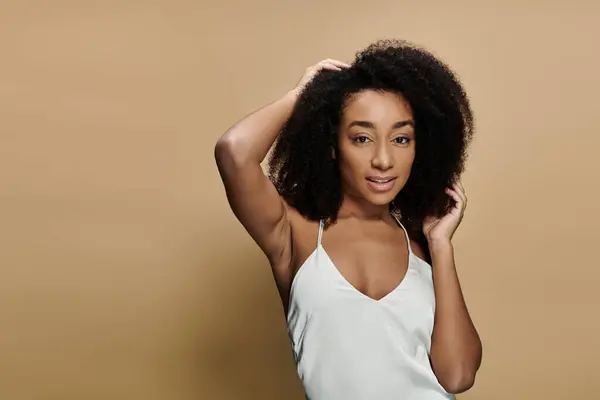 A beautiful African American woman with natural makeup smiles at the camera while running her hand through her hair. — Stock Photo