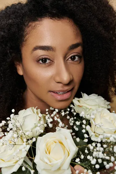 Um retrato de close-up de uma bela mulher afro-americana com maquiagem natural segurando um buquê de rosas brancas. — Fotografia de Stock
