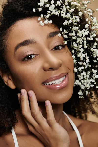 An African American woman with natural makeup and flowers in her hair smiles at the camera. — Stock Photo