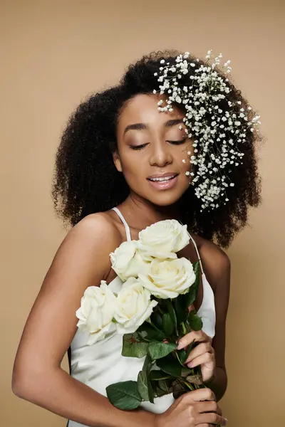 A beautiful African American woman with natural makeup holds white roses while babys breath blossoms cascade through her hair. — Stock Photo