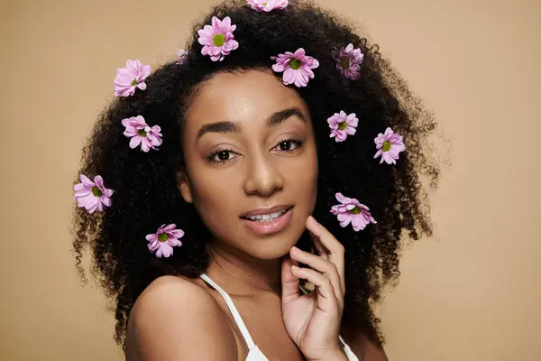 A close-up portrait of a beautiful African American woman with natural makeup, flowers in her hair, and a gentle smile. — Stock Photo