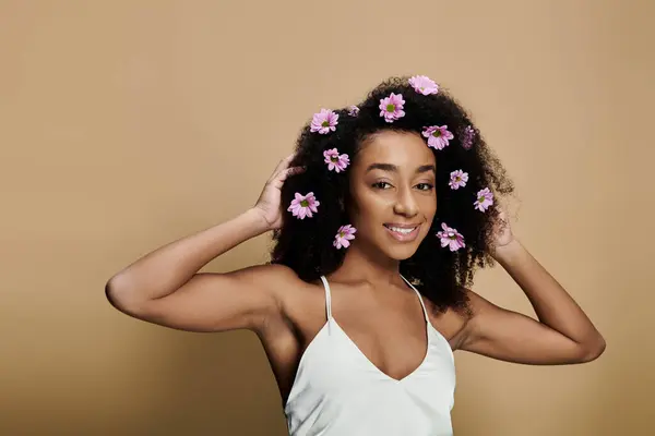 A beautiful African American woman with natural makeup and flowers in her hair smiles for the camera. — Stock Photo