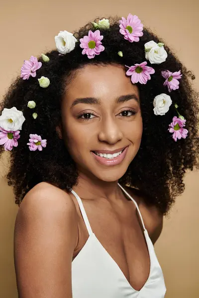 A beautiful African American woman with natural makeup and flowers in her hair smiles at the camera. — Stock Photo