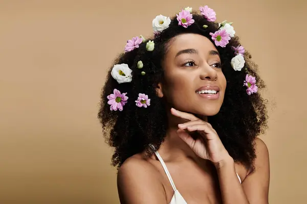 A beautiful African American woman with flowers in her hair smiles softly, looking off to the side. — Stock Photo