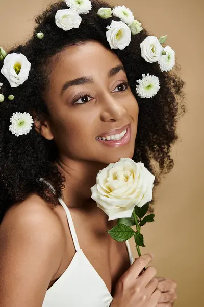 Uma bela mulher afro-americana com flores no cabelo sorri suavemente, mostrando sua beleza natural e graça. — Fotografia de Stock