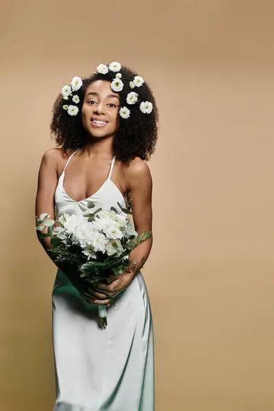 Una hermosa mujer afroamericana con maquillaje natural y flores en el pelo sonríe calurosamente para la cámara. - foto de stock