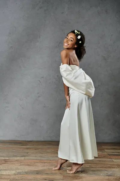 A beautiful African American bride in a white wedding dress with flowers in her hair smiles at the camera. — Stock Photo