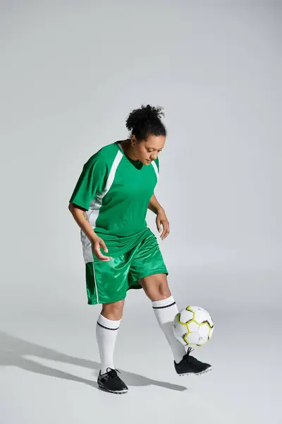 Una donna in uniforme da calcio verde sapientemente destreggia una palla. — Foto stock