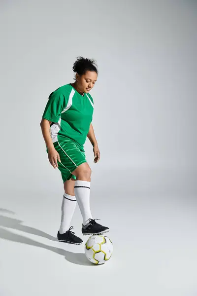 Female athlete in green jersey skillfully balances ball on foot. — Stock Photo