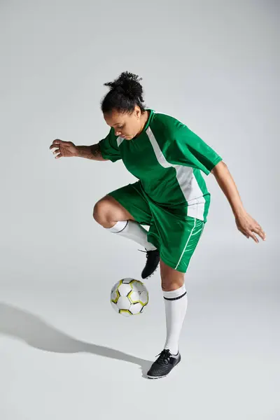 A woman in a green soccer uniform juggles the ball with athleticism. — Stock Photo