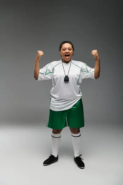 Une femme sportive en uniforme de football célèbre une victoire avec une pose triomphante. — Photo de stock