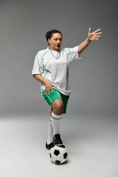 Une arbitre féminine se tient en confiance avec un sifflet à la main, prête à officialiser un match de football. — Photo de stock