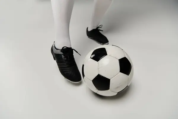Une femme en crampons de football se tient dans un studio avec un ballon à ses pieds. — Photo de stock