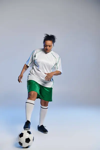 A woman in a white jersey and green shorts dribbles a soccer ball. — Stock Photo