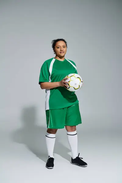 Un'atleta donna si trova fiduciosa con un pallone da calcio in mano, pronta per la partita. — Stock Photo