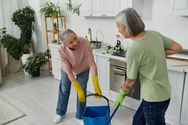 Un couple lesbien plus âgé nettoie sa cuisine moderne. — Photo de stock