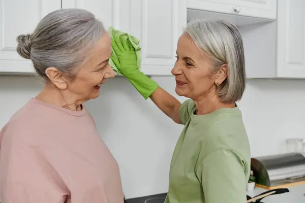 Two mature women, a lesbian couple, clean their modern kitchen together. — Stock Photo