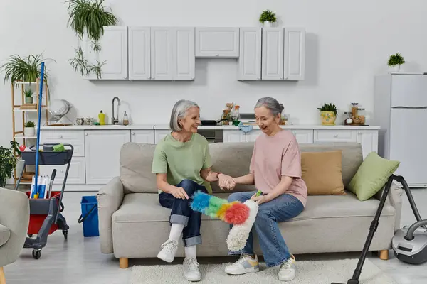 A mature lesbian couple enjoys cleaning their modern apartment together. — Stock Photo