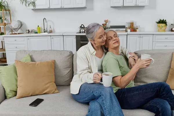 Um casal lésbico descansa em um sofá em seu apartamento moderno depois de terminar suas tarefas. — Fotografia de Stock