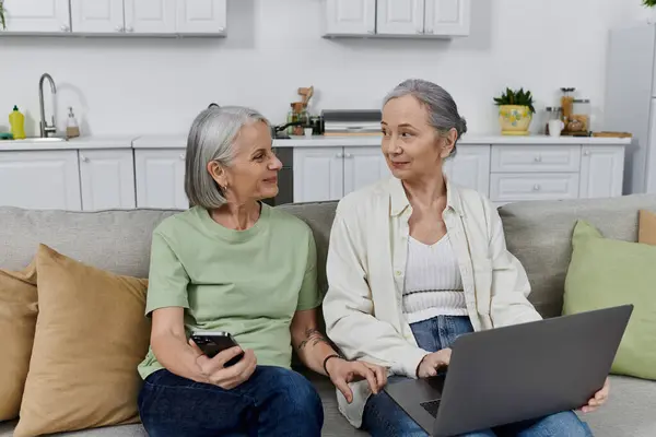 Two mature lesbian women rest on a couch after cleaning their modern apartment together. — Stock Photo