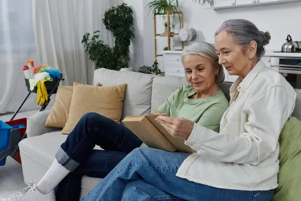 A lesbian couple rests on a couch after cleaning their modern apartment together, enjoying a moment of relaxation. — Stock Photo