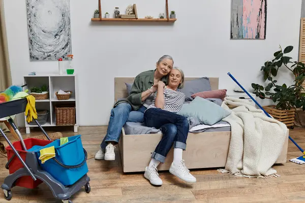 Um casal lésbico maduro relaxa em sua cama depois de limpar seu apartamento moderno. — Fotografia de Stock