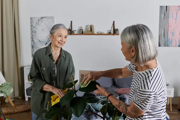 A lesbian couple in their 60s cleans their modern apartment together, smiling at each other as they work. — Stock Photo