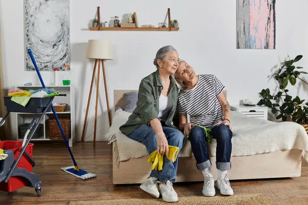 Duas mulheres lésbicas maduras relaxar em sua cama em um apartamento moderno após a limpeza, mostrando um relacionamento amoroso e uma casa confortável. — Fotografia de Stock