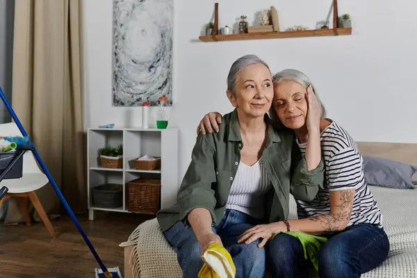Lesbian couple resting on bed in modern apartment, showing affection as one woman rests head on others shoulder. — Stock Photo