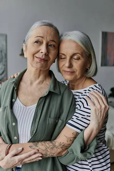 Two mature women embrace each other in a modern apartment setting, expressing their love and affection. — Stock Photo