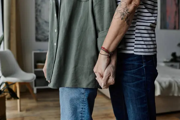 A mature lesbian couple holds hands and hugs in their modern apartment. — Stock Photo