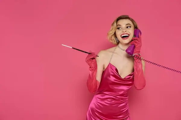 A stylish woman in a pink dress conversing on a phone. — Stock Photo