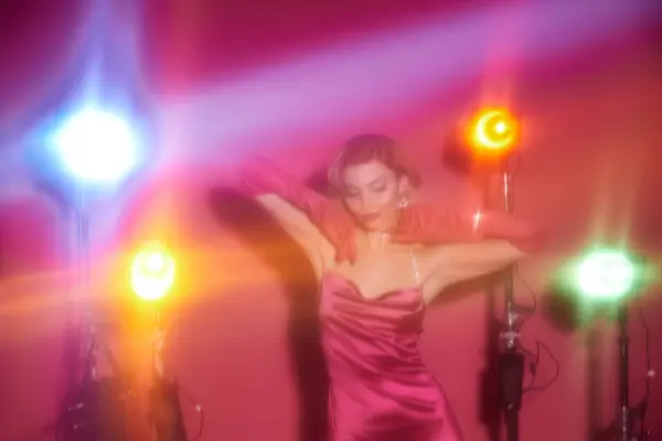 Uma mulher em um vestido rosa vibrante dança sob luzes coloridas. — Fotografia de Stock