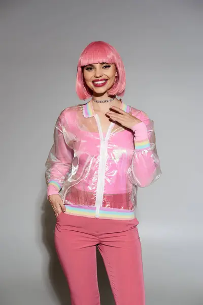 Una mujer con una peluca rosa y una chaqueta clara con adornos de arco iris sonríe a la cámara. — Stock Photo