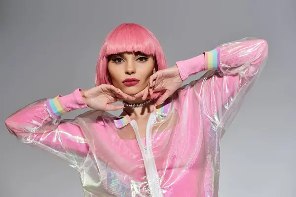 A woman with pink hair poses in a transparent pink jacket with rainbow trim. — Stock Photo