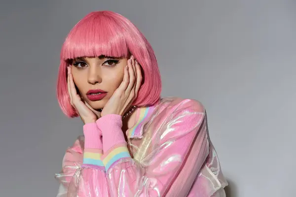 A young woman with pink hair and a vibrant pink jacket poses against a gray background. — Stock Photo