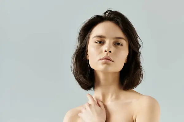 Une belle femme aux cheveux foncés pose sur un fond gris clair. — Photo de stock