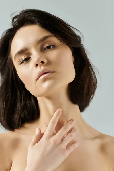 A close-up portrait of a woman with dark hair, her hand gently resting on her neck. — Stock Photo