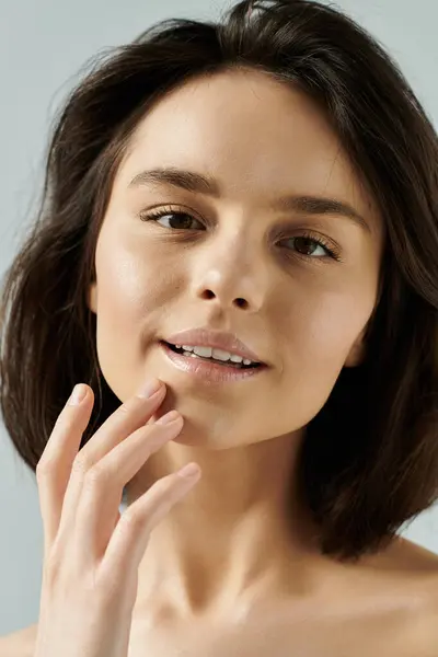 A woman with dark hair poses against a light background, her hand gently resting on her cheek. — Stock Photo