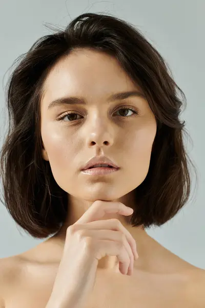 A woman with short, dark hair contemplates in front of a simple background. — Stock Photo