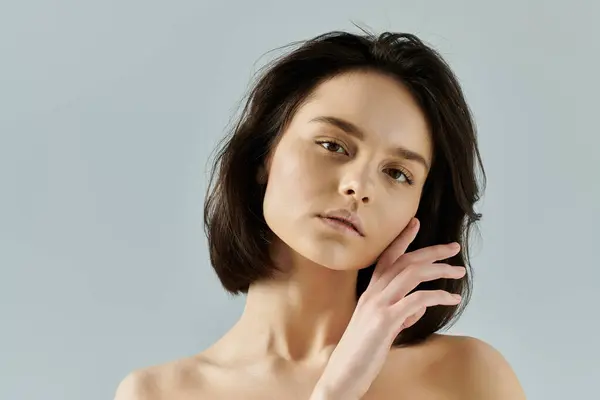 Retrato de una mujer de cabello oscuro posando sobre un fondo azul claro. - foto de stock