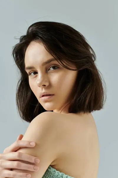 Una donna con i capelli scuri e un'espressione gentile posa su uno sfondo semplice. — Foto stock