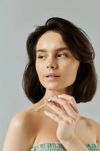 Una joven con el pelo corto y oscuro posa mientras sostiene una botella de suero. — Stock Photo