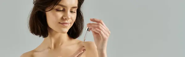 Женщина наносит сыворотку на кожу в студии. — стоковое фото