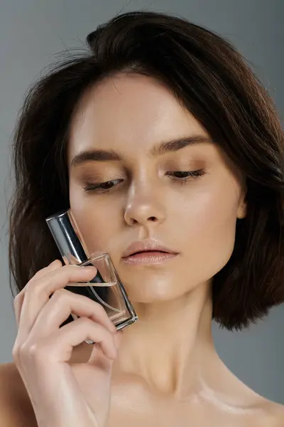 Una joven sostiene una botella de perfume, su rostro enfocado en la fragancia. — Stock Photo